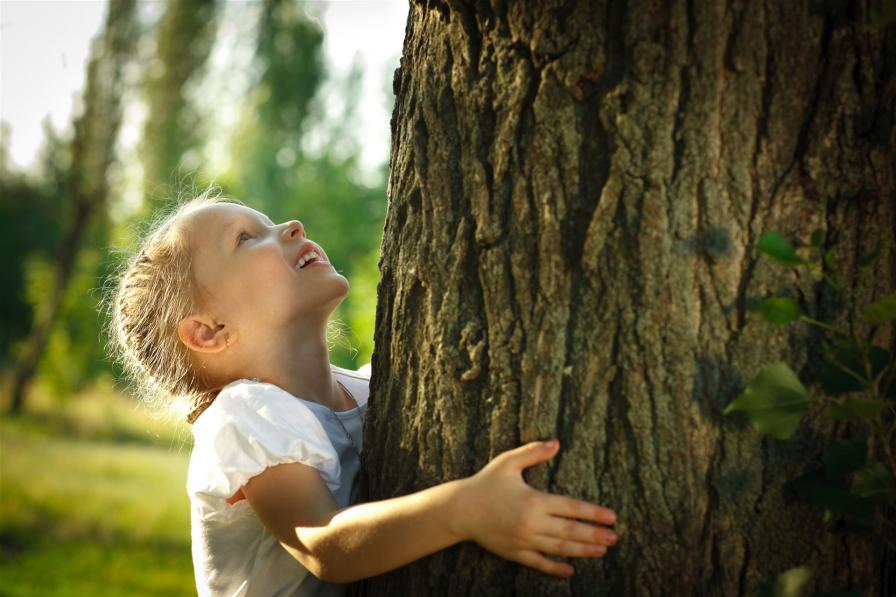 Mädchen umarmt einen Baum, Natur erleben im Haus der Kinder im Spessart